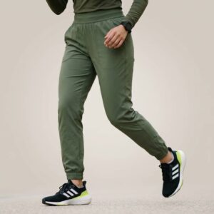 Close-up of a person wearing green pants with a neutral background